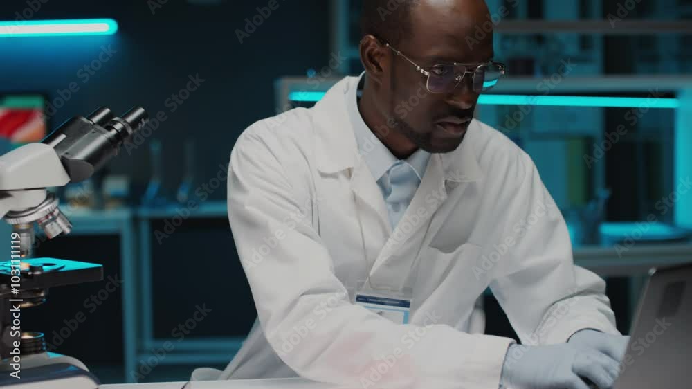 Tilt down shot of African American food scientist in sterile gloves and ...