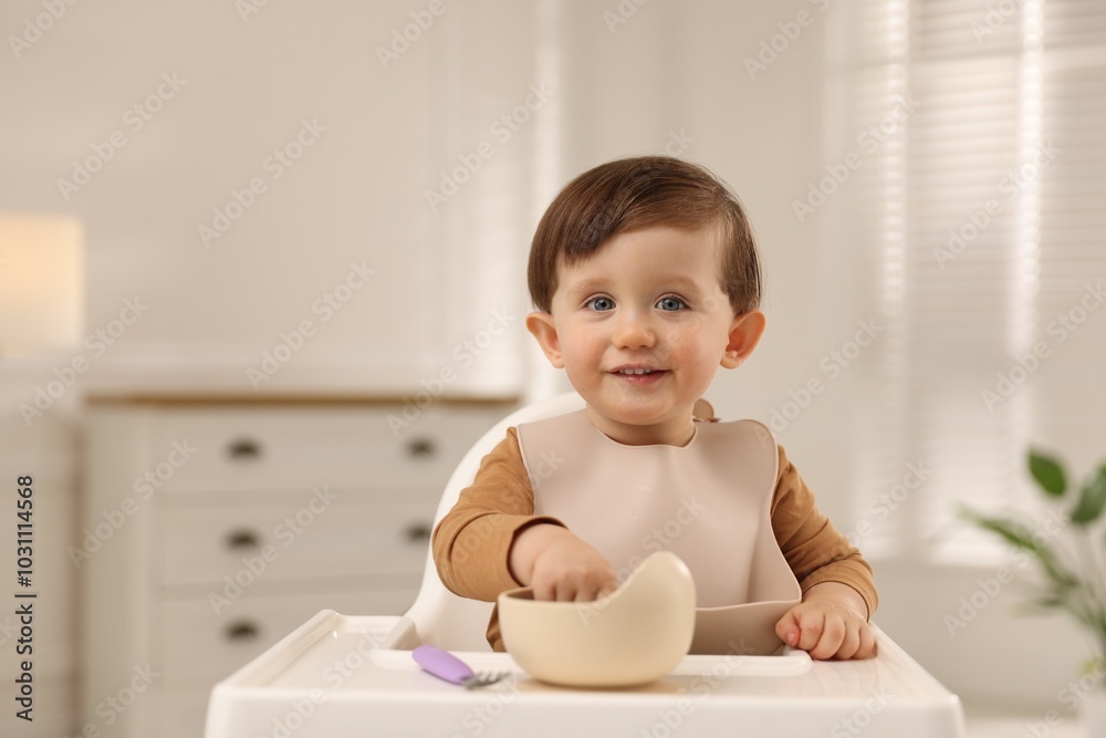 Cute little baby eating healthy food from bowl in high chair at home, space for text Cute little baby eating healthy food from bowl in high chair at home, space for text