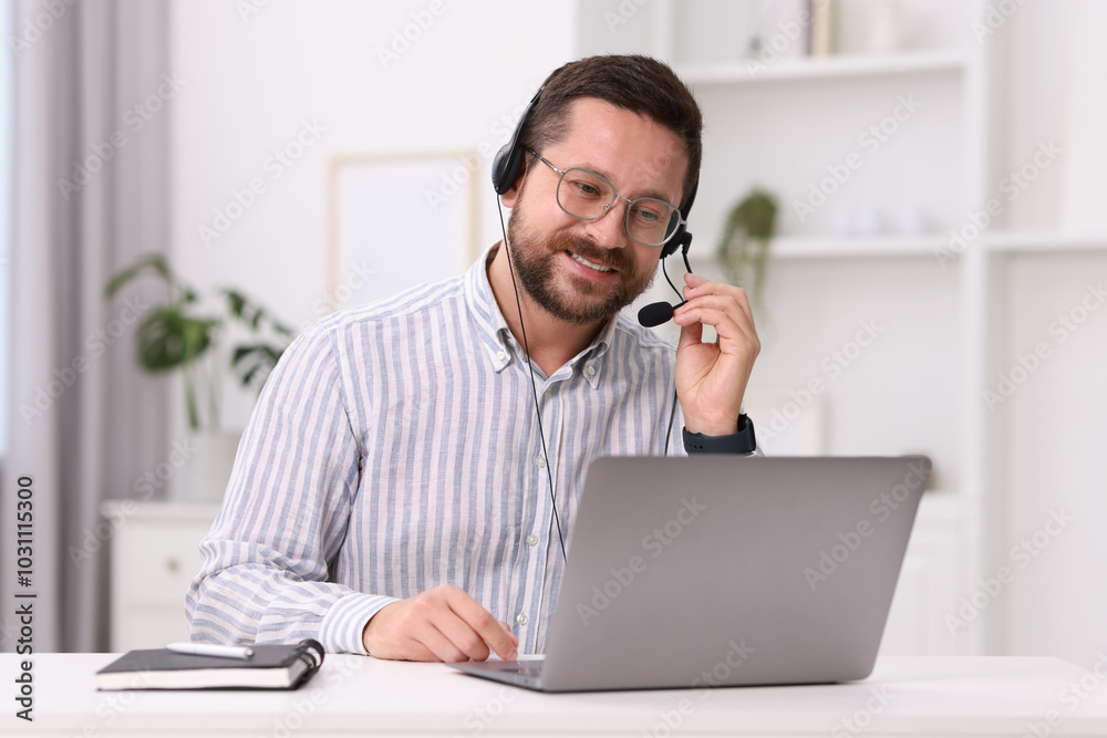 Interpreter in headset having video chat via laptop at white table indoors Interpreter in headset having video chat via laptop at white table indoors