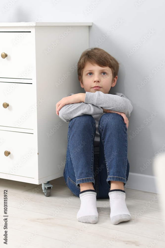 Autism concept. Lonely little boy on floor near grey wall at home Autism concept. Lonely little boy on floor near grey wall at home