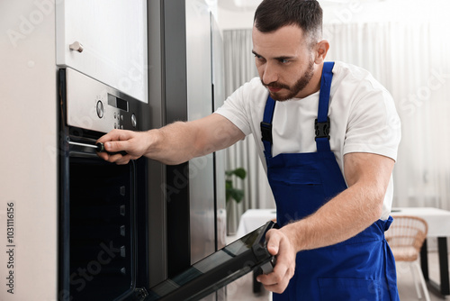 Repairman with screwdriver fixing oven at home