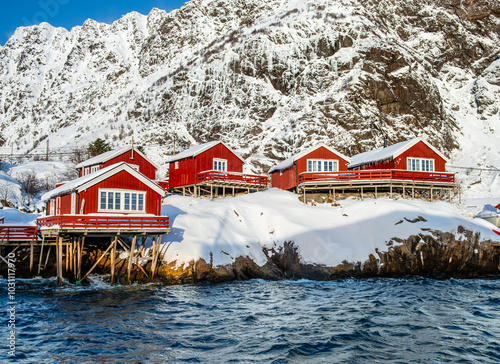 A i Lofoten village with traditional red wooden fishermen cabins on stilts in water, called rorbu, on Lofoten islands in winter. Snowy Scandinavian landscape in northern Norway photo