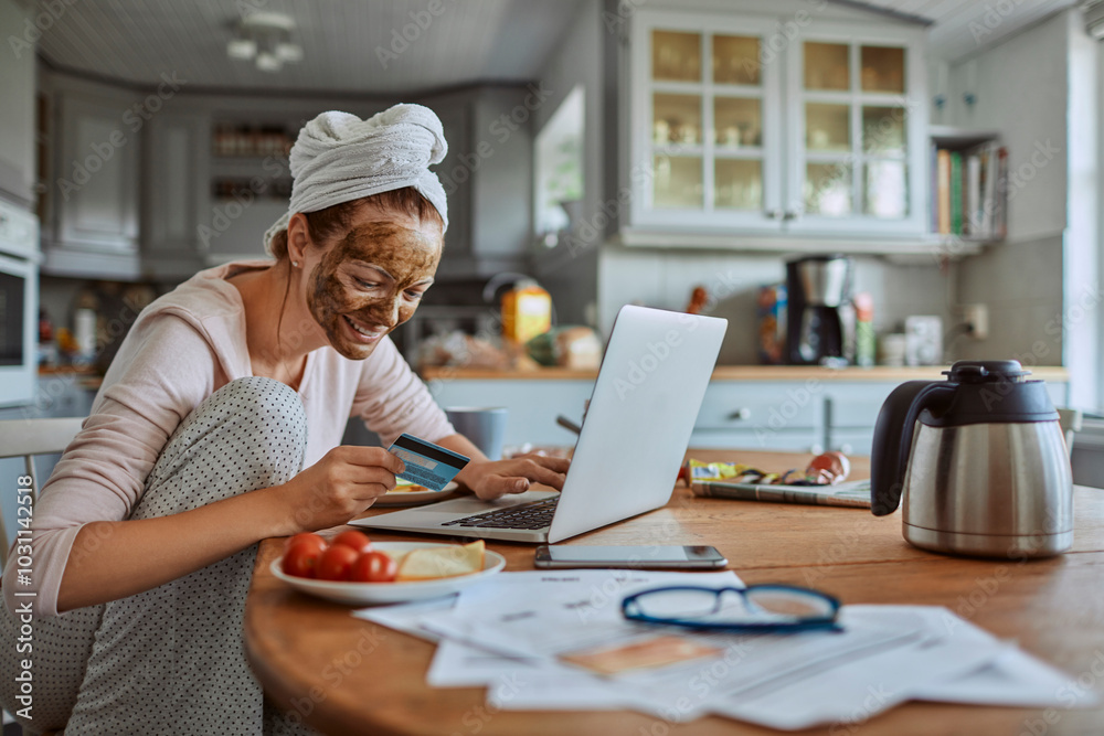 Woman with face mask using laptop in the morning at kitchen table Woman with face mask using laptop in the morning at kitchen table