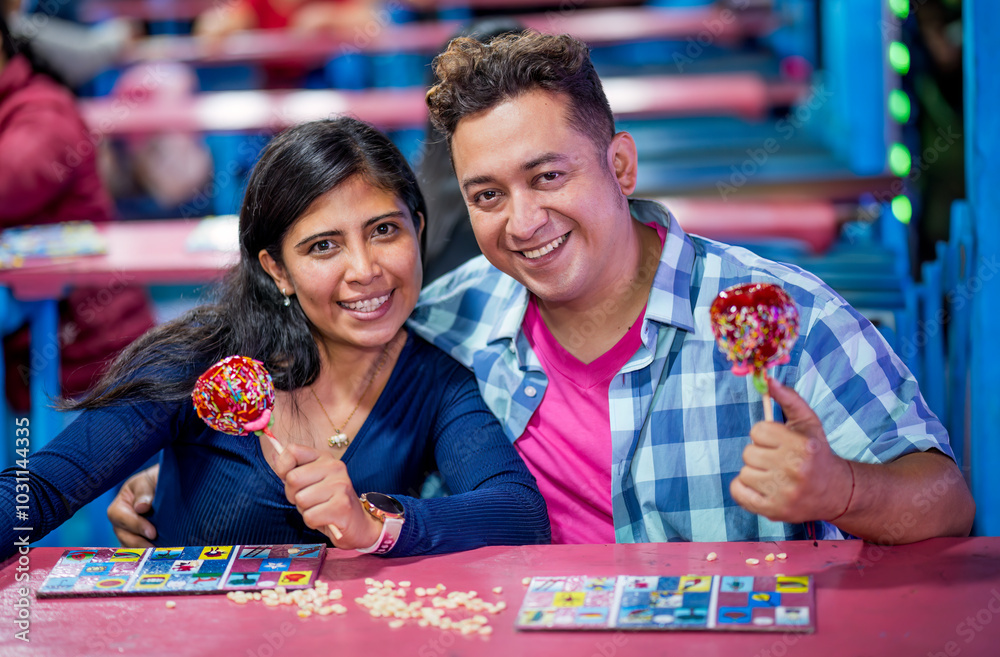 Portrait of friends playing the lottery at their city fair, they hold in their hands a red apple with caramel and candy toppings of various colors. Portrait of friends playing the lottery at their city fair, they hold in their hands a red apple with caramel and candy toppings of various colors.