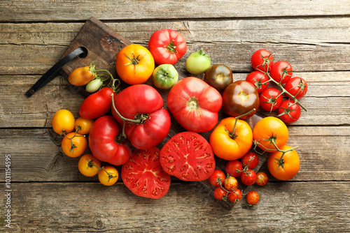 Different ripe tomatoes on wooden table, top view