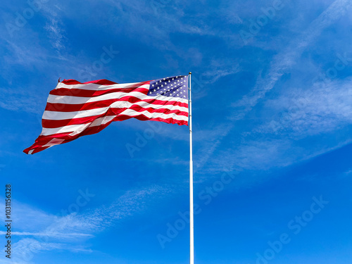 Very large American Flag blowing in the wind against a deep blue sky