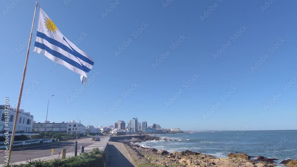 Flag of Uruguay with flagpole waving in wind. Uruguayan flag waving with the summer breeze. Punta de las Salinas, Punta del Este, Uruguay | 4K | Horizontal Video