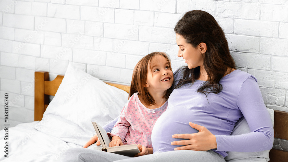 Preschool girl discussing book with her pregnant mom, bedroom interior, free space Preschool girl discussing book with her pregnant mom, bedroom interior, free space
