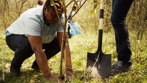 Volunteers filling up holes after planting trees around the forest, contributing to environmental protection and restore nature. Activists social team growing seeds in the woods habitat. Camera B.