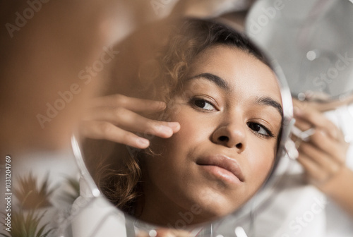 Cuadro en lienzo Afro-american girl looking herself in round mirror in bathroom.