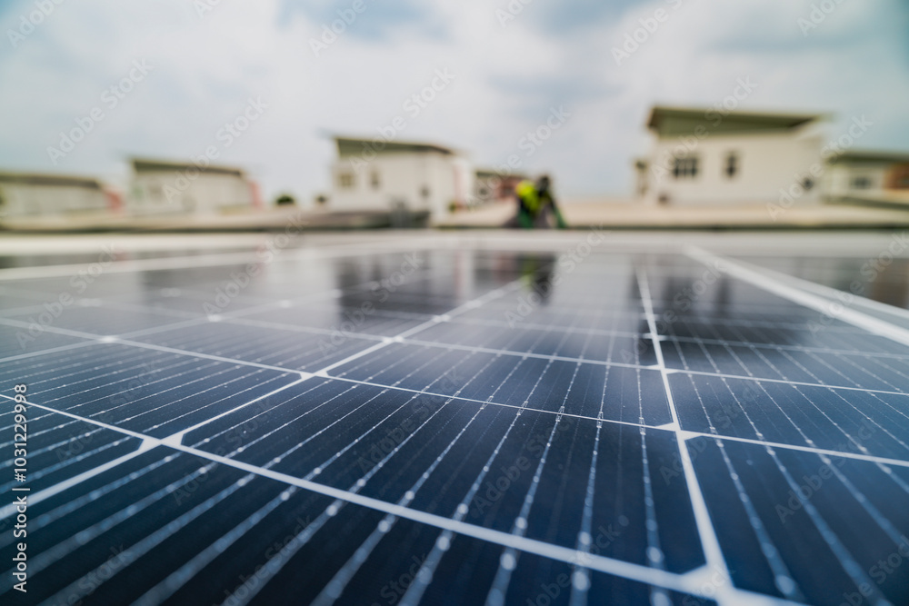 Fototapeta premium A close up of solar panels with a worker blurred in the background. The focus on the panels emphasizes the importance of renewable energy technology and solar power installations.