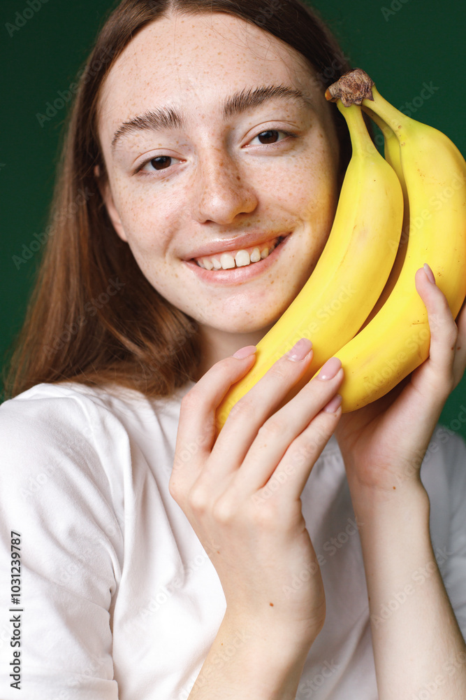 Studio portrait of a girl holding two bananas isolated on green background Studio portrait of a girl holding two bananas isolated on green background