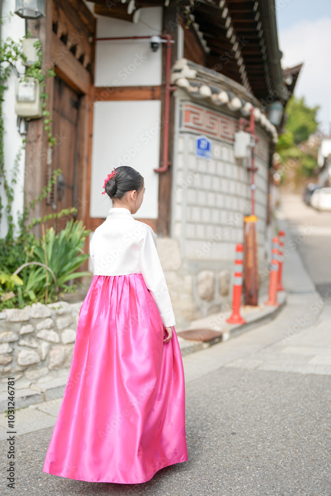 Fototapeta premium A 9-year-old Korean girl wearing a hanbok is walking through the historic streets of Gyedong-gil, Jongno District, Seoul, Korea.