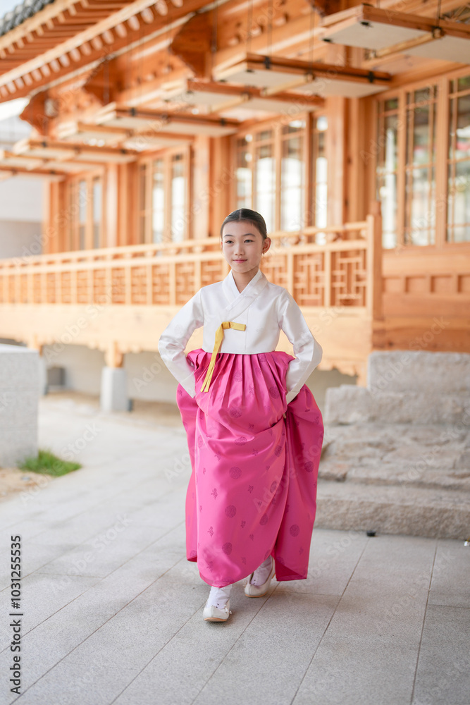 A 9-year-old Korean girl wearing a hanbok is performing a traditional dance in front of a traditional building in the historic town of Gyedong-gil, Jongno District, Seoul, Korea. A 9-year-old Korean girl wearing a hanbok is performing a traditional dance in front of a traditional building in the historic town of Gyedong-gil, Jongno District, Seoul, Korea.