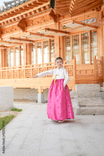 A 9-year-old Korean girl wearing a hanbok is performing a traditional dance in front of a traditional building in the historic town of Gyedong-gil, Jongno District, Seoul, Korea.