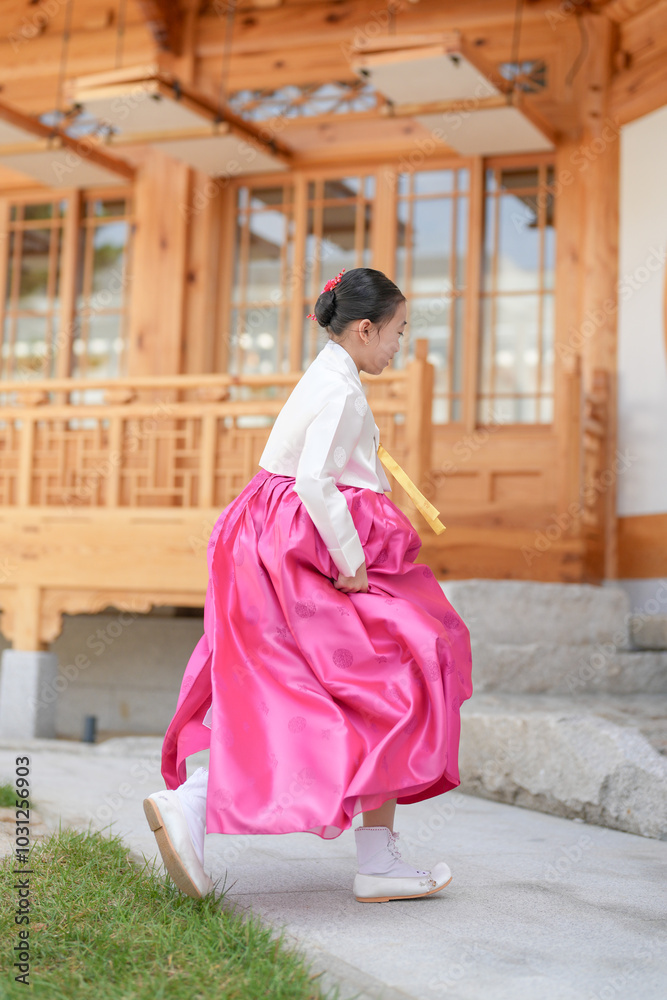 Fototapeta premium A 9-year-old Korean girl wearing a hanbok is performing a traditional dance in front of a traditional building in the historic town of Gyedong-gil, Jongno District, Seoul, Korea.