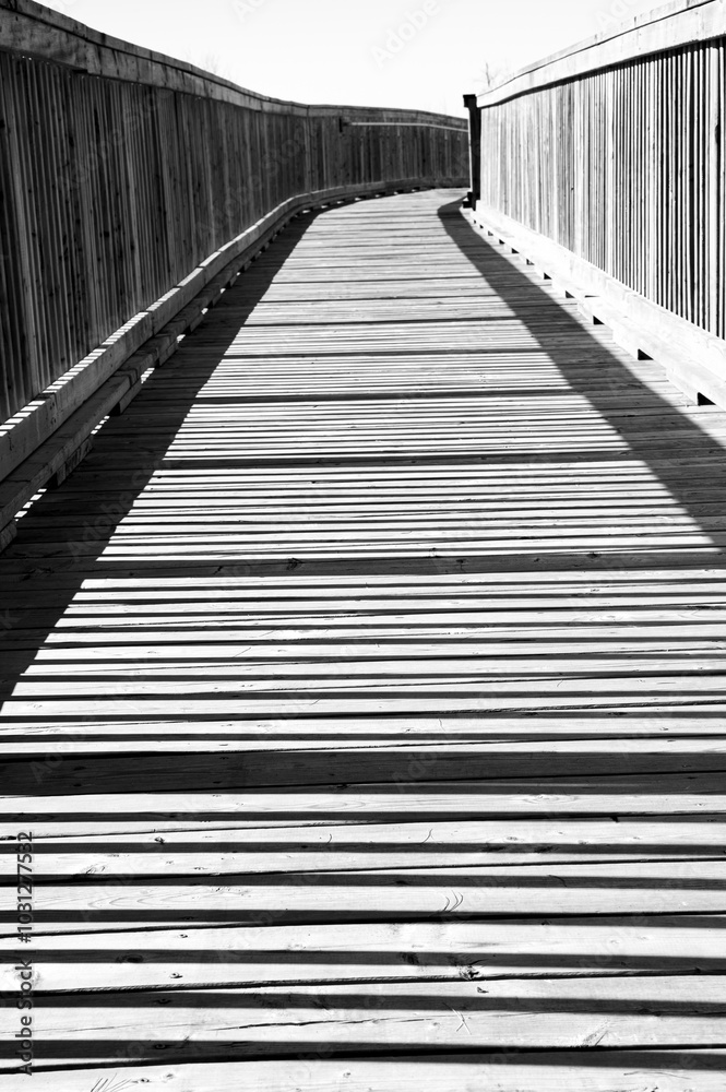 Black and White Wooden Walkway with Shadows from the Railing Creating a Pattern Black and White Wooden Walkway with Shadows from the Railing Creating a Pattern