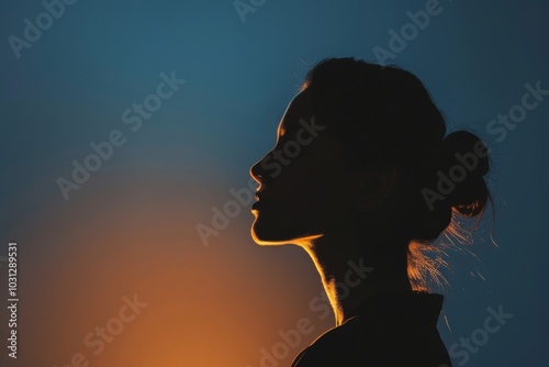 A woman's silhouette stands against a beautiful sunset sky, creating a dramatic and artistic image.