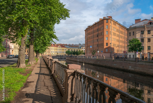 View of a residential building in the shape of an iron on the embankment of the Griboyedov Canal on a sunny day, St. Petersburg, Russia