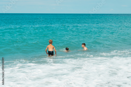 A group of children swim in the turquoise sea on summer holidays