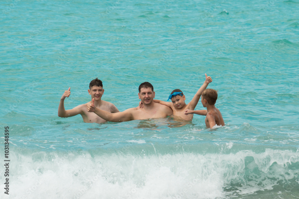 Father and sons swim in the turquoise sea Father and sons swim in the turquoise sea