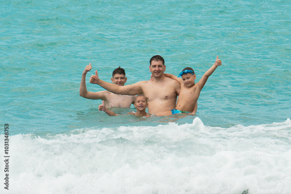 Father and sons swim in the turquoise sea Father and sons swim in the turquoise sea