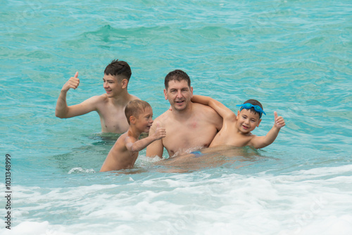 Father and sons swim in the turquoise sea