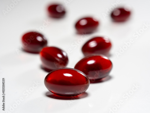 Krill oil capsules on white background. Translucent red softgel capsules of antarctic krill oil. Cardiovascular health. Nutritional supplement with valuable substances