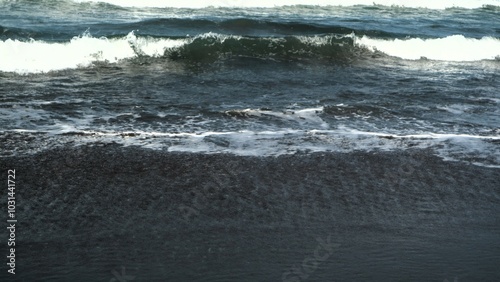 Waves crashing against the shore with a clear blue sky in the background at Parangtritis Beach, Yogyakarta.