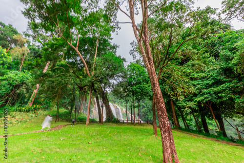 Natural blurred background of waterfalls, fast-flowing currents and water droplets from the wind blowing among the rocks and surrounded by big trees, spontaneous beauty photo