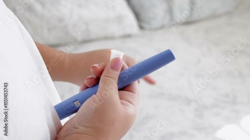 A young woman screws a needle on pre-filled pen injector to prepare it for taking medicine