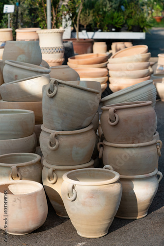 Vertical photo variety of clay pots in different sizes and shapes are neatly stacked outside a garden supply store, perfect for gardening enthusiasts and landscaping projects. Flower pots and vases