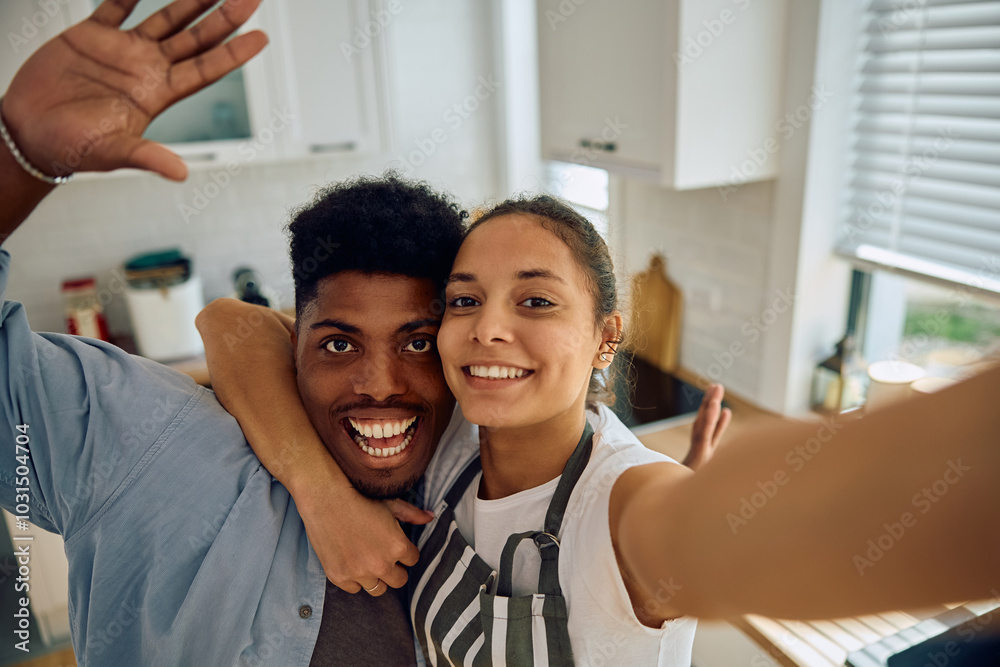 Cheerful couple taking selfie in kitchen and looking at camera. Cheerful couple taking selfie in kitchen and looking at camera.