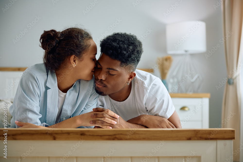 Affectionate woman kissing her boyfriend while relaxing on bed. Affectionate woman kissing her boyfriend while relaxing on bed.