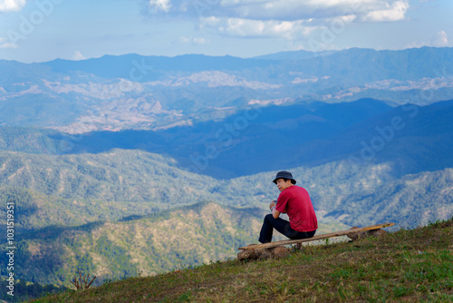 Asian man relaxes with the beautiful natural scenery of the sea of mist in the morning at Doi Ba Lu Kho Mountain View Point, Mae Chaem, Chiang Mai, Northern Thailand. photo