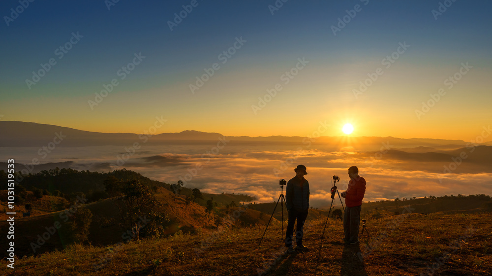 Asian man takes a photo of the beautiful natural scenery of the sea of mist in the morning at Doi Ba Lu Kho Mountain View Point, Mae Chaem, Chiang Mai, Northern Thailand. Asian man takes a photo of the beautiful natural scenery of the sea of mist in the morning at Doi Ba Lu Kho Mountain View Point, Mae Chaem, Chiang Mai, Northern Thailand.