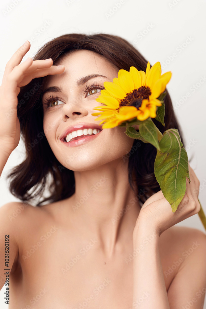 Happy woman holding a sunflower in front of her face with a big smile Happy woman holding a sunflower in front of her face with a big smile