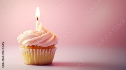 A single cupcake with a lit candle on a pink background.