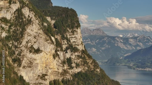 Close-up view of massive stone cliffs towering over Lake Walensee in the Swiss Alps. Drone 4k.
