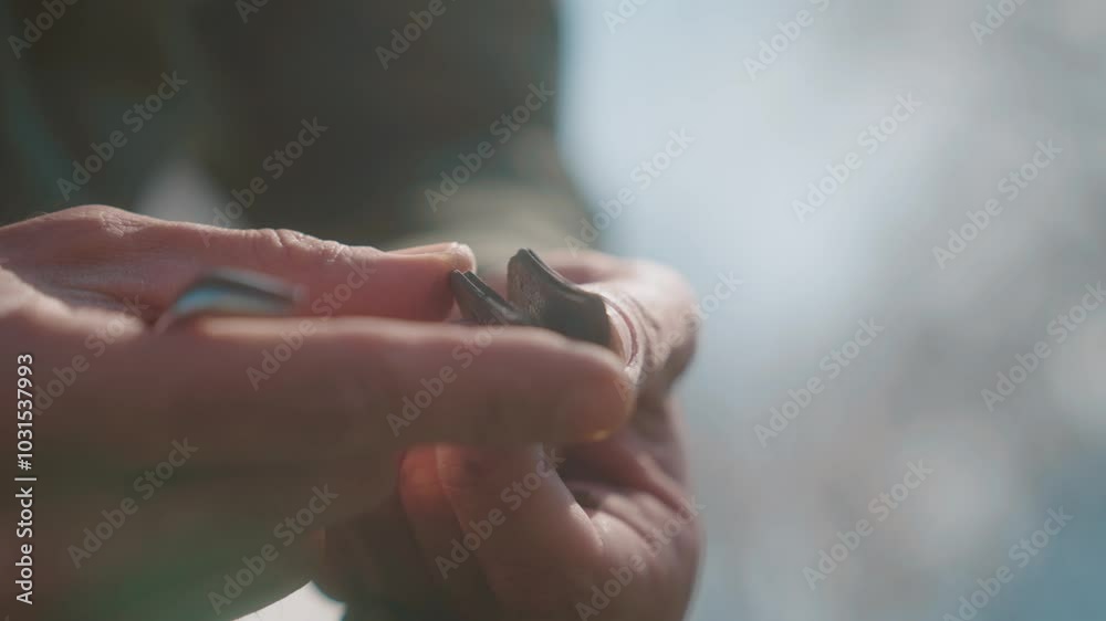 A close-up of hands adjusting a small tool outdoors with soft sunlight shining in the background A close-up of hands adjusting a small tool outdoors with soft sunlight shining in the background