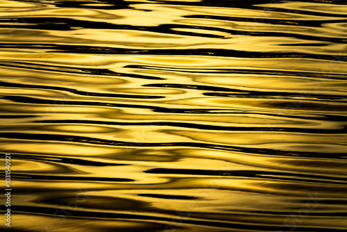 The image is of a body of water with ripples and waves. The water appears to be a golden color, which gives the scene a warm and peaceful feeling. The ripples and waves create a sense of movement