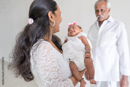 ndian family spending time together, wearing traditional and casual outfits with a baby, a young girl, and grandparents in a high-rise apartment in Kuala Lumpur, Malaysia. photo