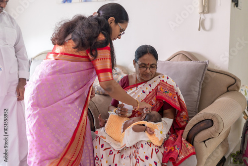 ndian family spending time together, wearing traditional and casual outfits with a baby, a young girl, and grandparents in a high-rise apartment in Kuala Lumpur, Malaysia. photo