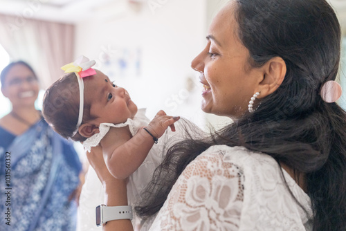 ndian family spending time together, wearing traditional and casual outfits with a baby, a young girl, and grandparents in a high-rise apartment in Kuala Lumpur, Malaysia. photo