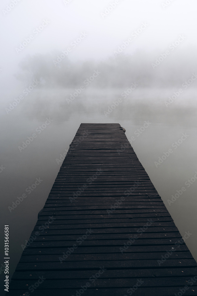 Fototapeta premium Minimalist foggy pier over still water on a misty morning