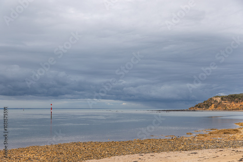 Calm sea, stormy sky and rocky shore in Barwon Heads, Victoria photo