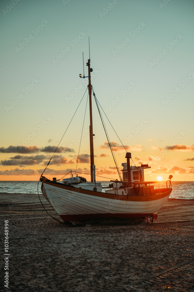 Fishing boat on Slettestrand Beach, Denmark, at sunset by the sea