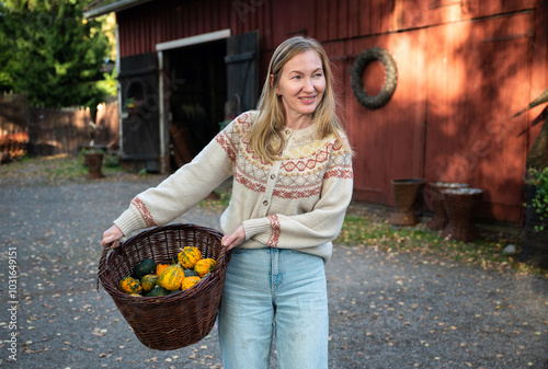 Woman holding decorative pumpkins in wicker basket. photo