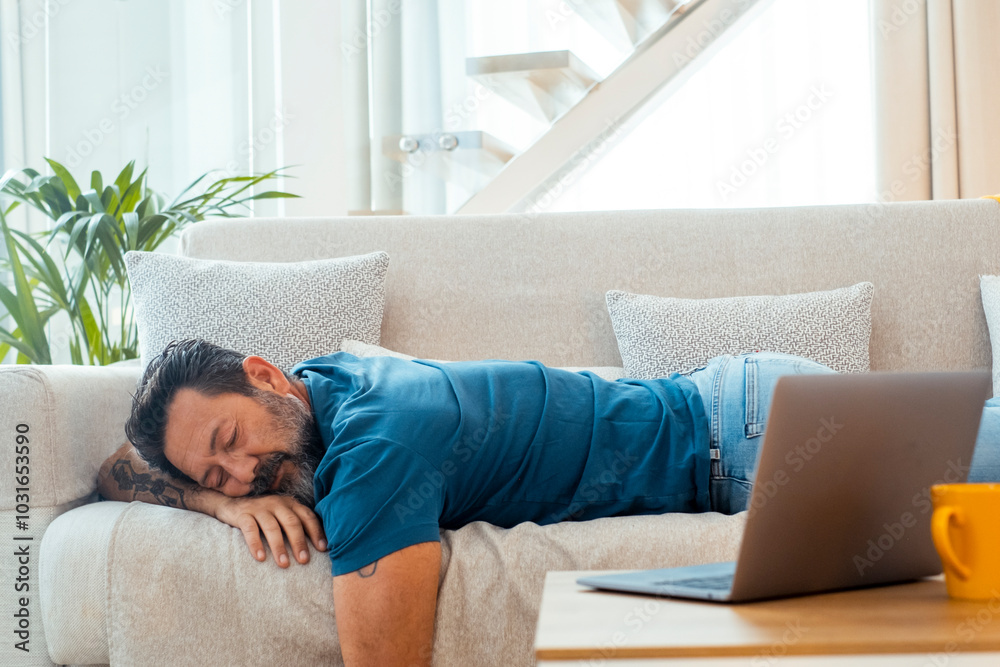Exhausted man taking a midday nap on his sofa, sleeping peacefully in a comfortable position, embodying the concept of stress relief and relaxation during a cozy afternoon at home Exhausted man taking a midday nap on his sofa, sleeping peacefully in a comfortable position, embodying the concept of stress relief and relaxation during a cozy afternoon at home