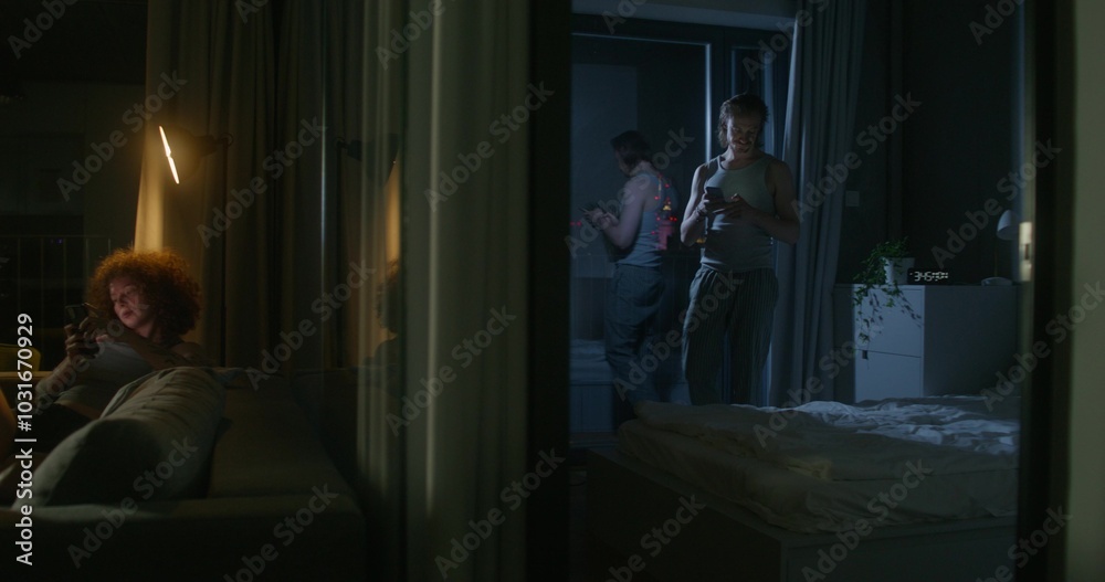 A woman uses a mobile phone sitting on the couch at home. The man throws the phone on the bed and lies down. He's upset. Home interior, night A woman uses a mobile phone sitting on the couch at home. The man throws the phone on the bed and lies down. He's upset. Home interior, night